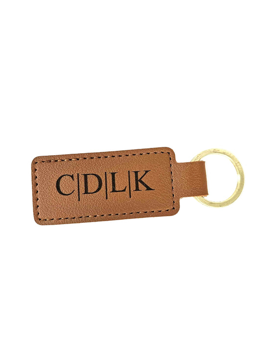 Brown leather keychain with gold ring and engraved initials on a white background